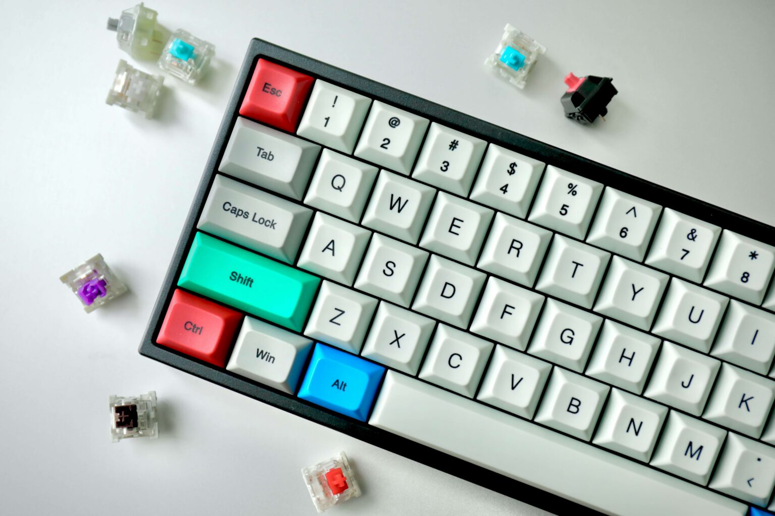 Mechanische Tastatur mit bunten Tasten und mehreren losen Switches auf weißem Hintergrund.